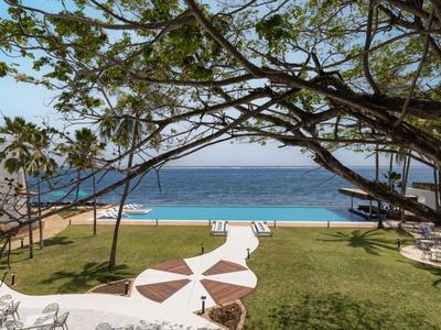 Blick auf einen gepflegten Garten und einen Pool mit Blick auf das Meer und den Himmel.