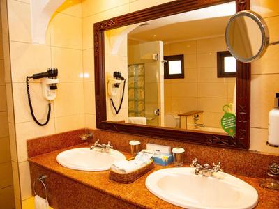 Salle de bain moderne avec deux lavabos, grand miroir et sèche-cheveux.