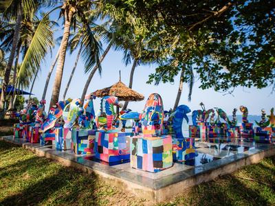 Bunte steinerne Tierfiguren vor Palmen auf einer Rasenfläche bei sonnigem Wetter
