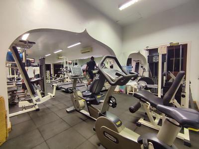 Fitnessraum mit verschiedenen Trainingsgeräten und Spiegeln an der Wand.