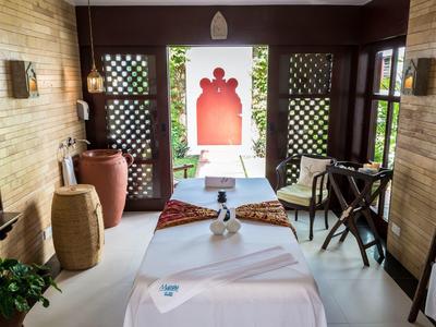 Un espace de massage calme avec deux tables, des coussins et une vue ouverte vers l'extérieur.