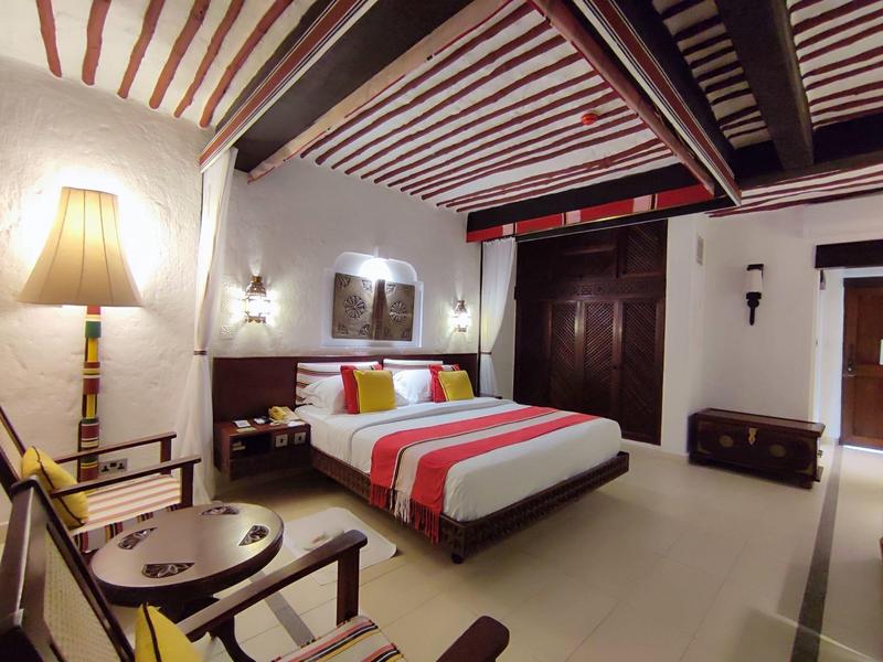 Deux hommes jouent au padel sur un court bleu devant des spectateurs et des palmiers.