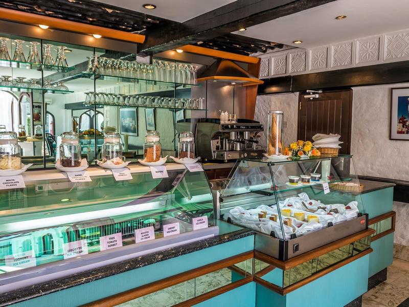 Bar d'hôtel moderne avec vitrines éclairées et sélection de verres et plats.