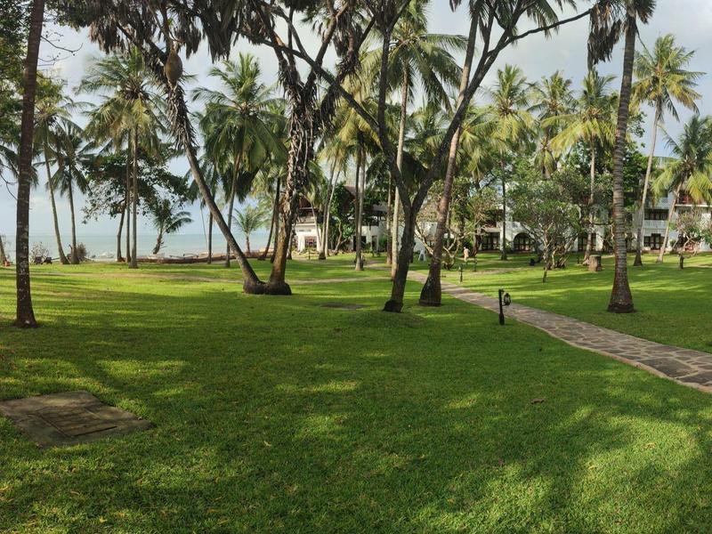 Grande pelouse avec des palmiers et un chemin dans une station tropicale.