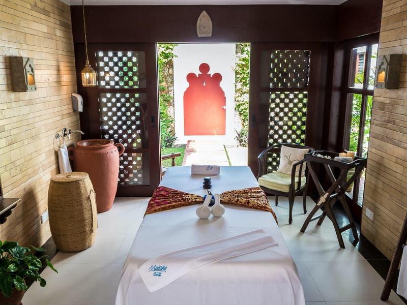 Un espace de massage calme avec deux tables, des coussins et une vue ouverte vers l'extérieur.