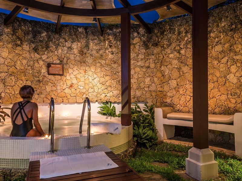 Bain à remous extérieur relaxant avec mur en pierre naturelle et sièges confortables en plein air.