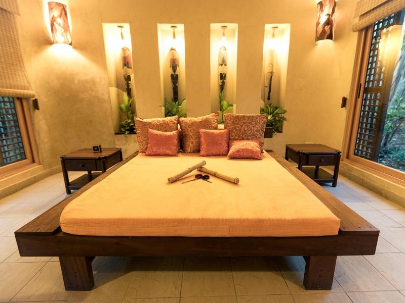 Pohodlný hotelový pokoj s velkou postelí, dekorativním osvětlením a bočními okny.