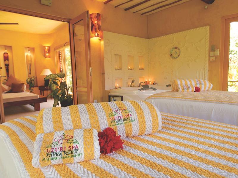 Světle zařízená wellness místnost se žluto-bílými pruhovanými ručníky a útulnou atmosférou.