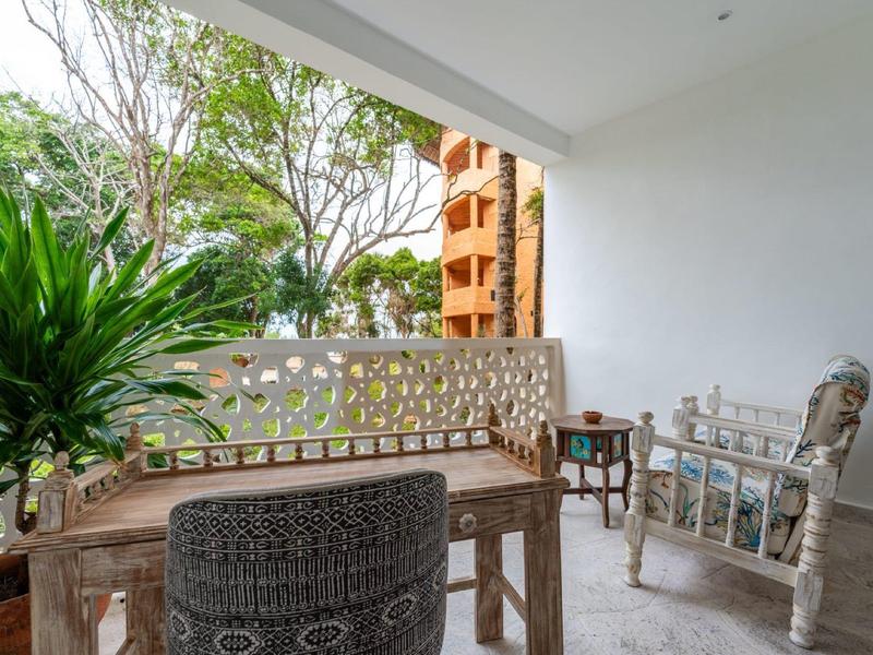 Salle de bain moderne avec murs blancs, lavabo, toilettes et douche avec porte en verre.