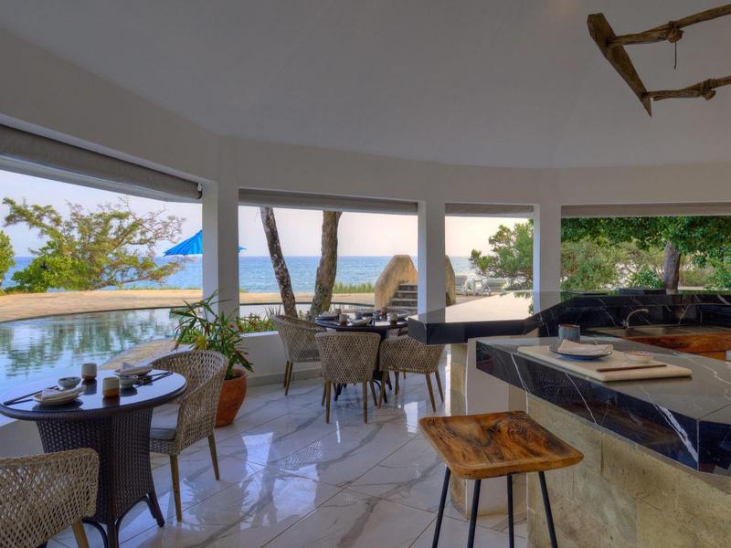 Espace lounge d'hôtel moderne avec tables et vue sur la piscine et la mer.