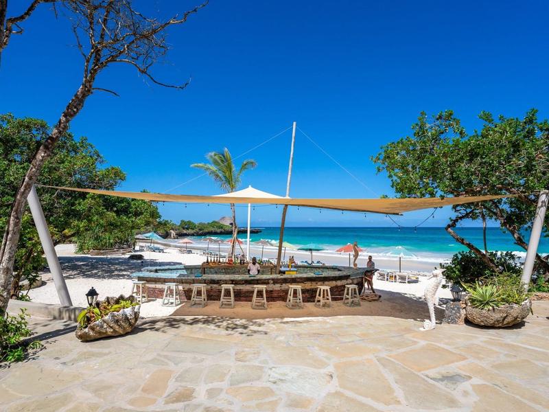 Bateau sur une plage de sable avec ciel bleu et plantes tropicales en arrière-plan