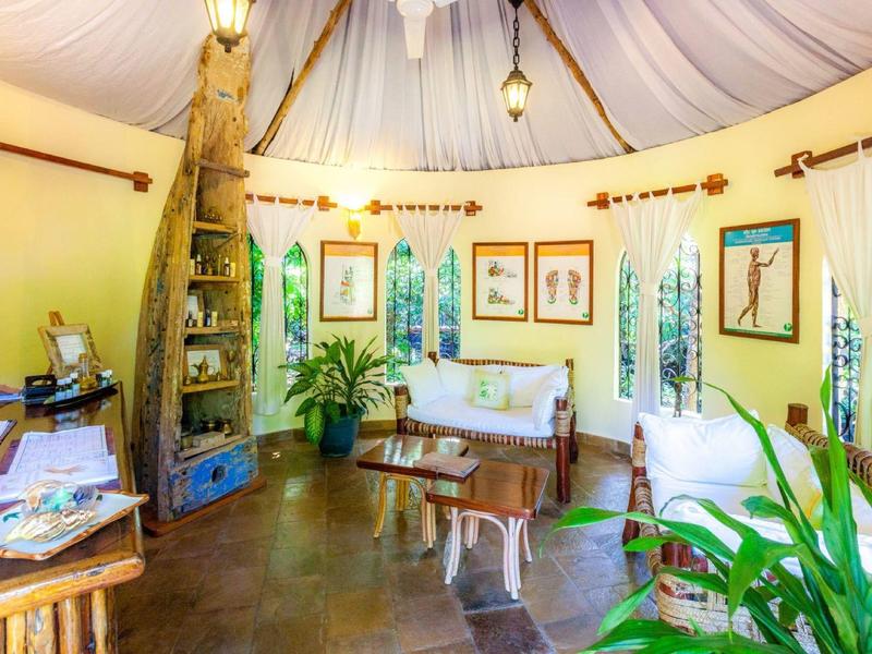 Intérieur de pièce ronde lumineuse et cosy avec meubles en bois, plantes et motifs animaliers aux murs.