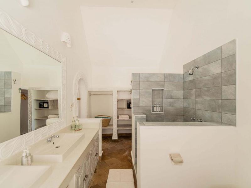 Salle de bain lumineuse avec double vasque, grand miroir et douche à l'italienne aux tons neutres.