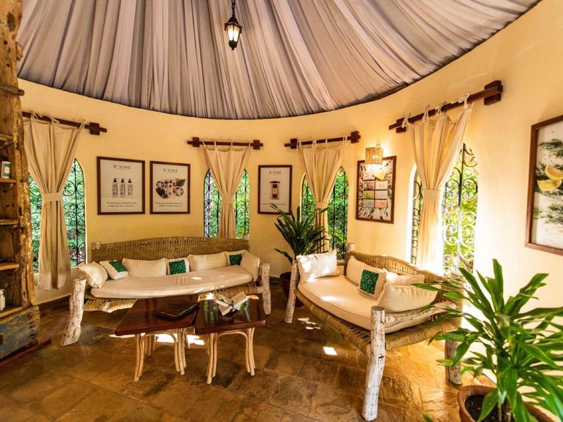 Espace de vie rond et confortable avec murs clairs, canapés et plantes pour des vacances détendues.