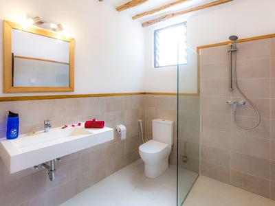 Bagno ben illuminato con lavabo, WC e doccia con parete in vetro.