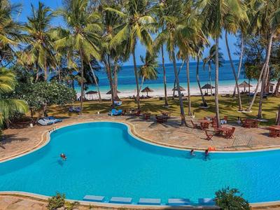 Grande piscina limpida circondata da palme con vista sulla spiaggia