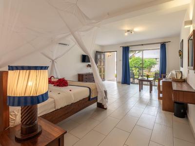 Camera luminosa con letto matrimoniale, lampada da comodino e terrazza con vista sul giardino.