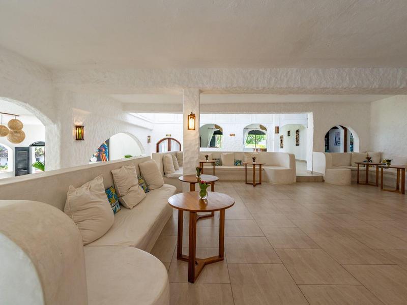 Area lounge luminosa con panca imbottita curva e arredamento minimalista in un hotel.