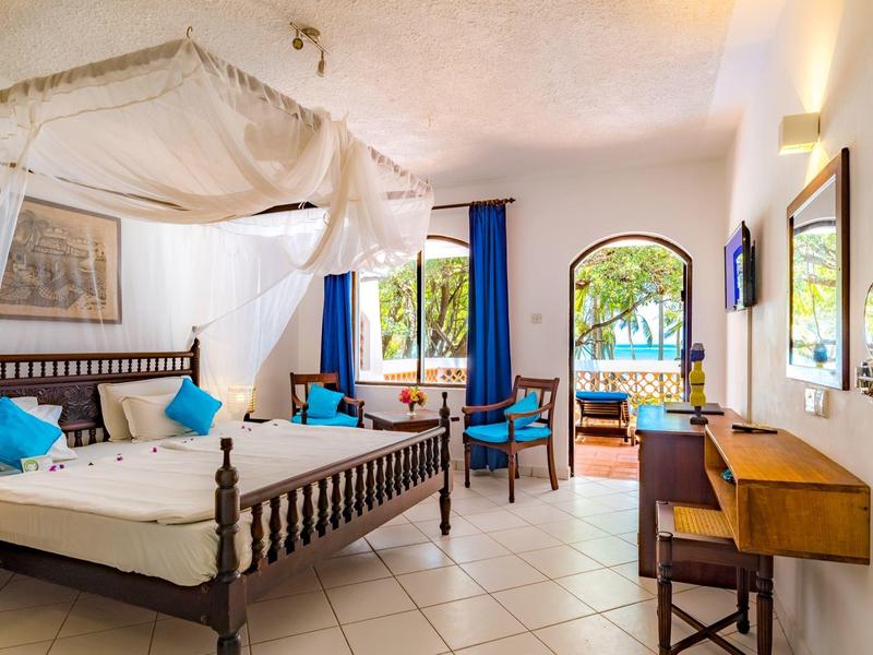 Camera d'hotel luminosa con letto a baldacchino, balcone e vista mare.