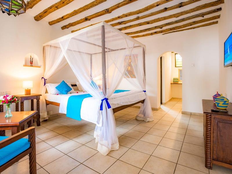 Camera d'albergo luminosa con letto a baldacchino e accenti blu.