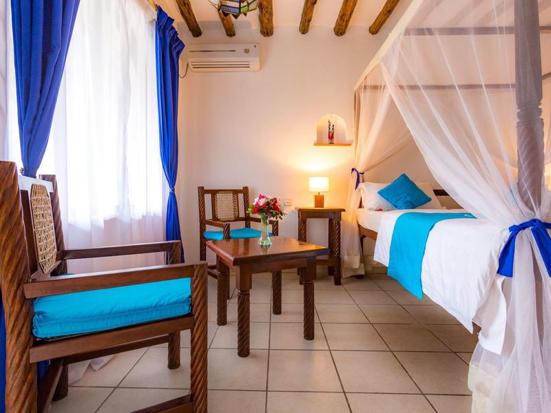 Camera luminosa arredata con biancheria da letto blu e bianca e mobili in legno.