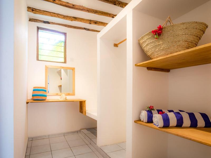 Spazio spogliatoio luminoso e moderno con travi in legno, scaffali e asciugamani in un hotel.