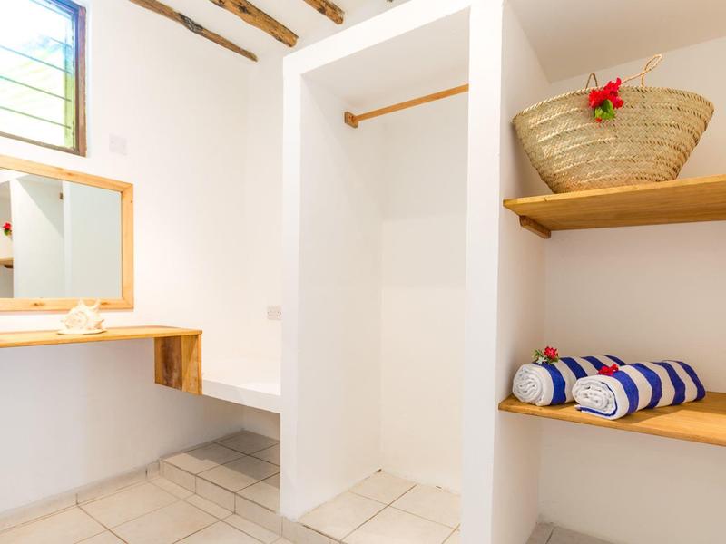 Spogliatoio luminoso con pareti bianche, panche in legno e asciugamani a righe.