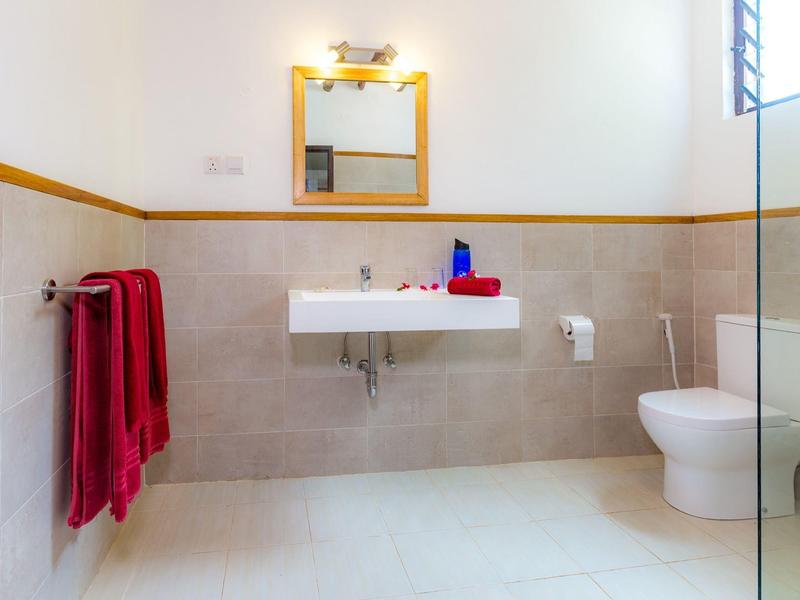 Bagno luminoso con lavabo bianco, WC e asciugamani rossi appesi al muro.