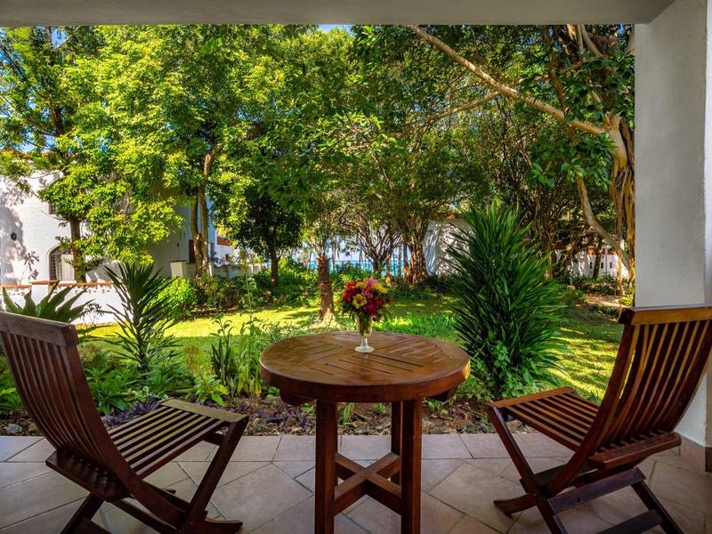 Accogliente patio con tavolo in legno e due sedie con vista su un giardino verde.