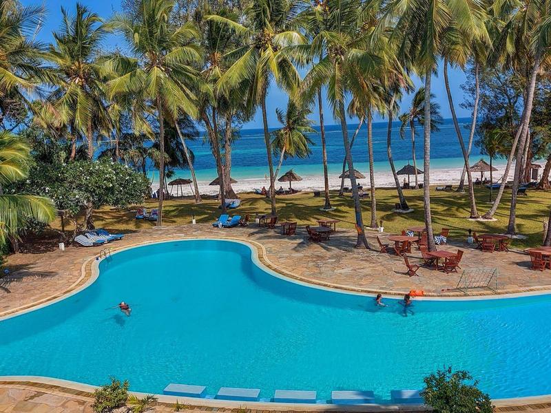 Grande piscina limpida circondata da palme con vista sulla spiaggia
