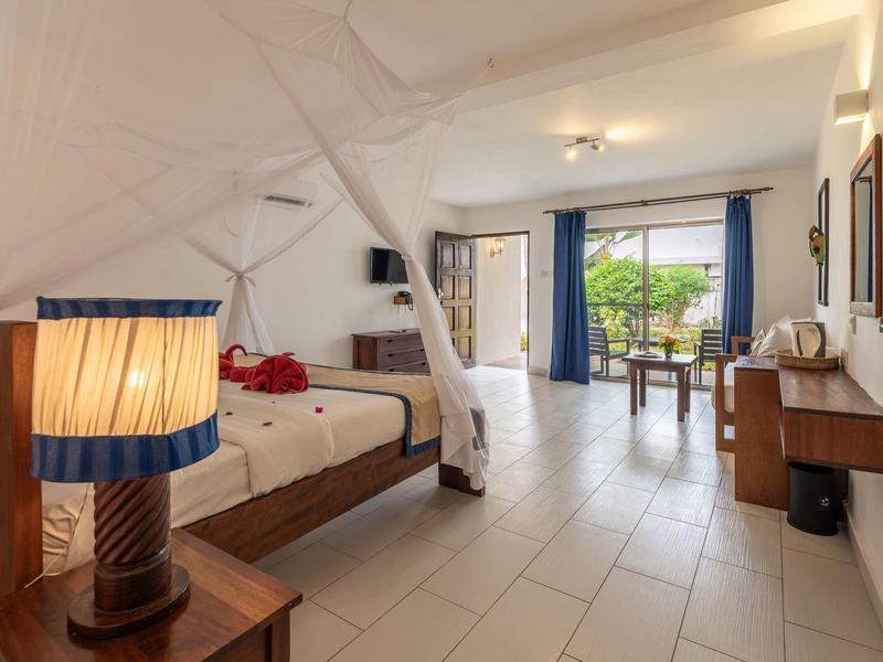 Camera luminosa con letto matrimoniale, lampada da comodino e terrazza con vista sul giardino.