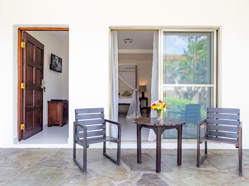 Patio con due sedie e un tavolo di fronte a porta e finestra della stanza aperte