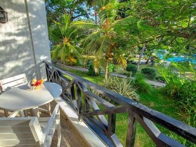 Balkon met wit tafel en stoelen met uitzicht op een tropische tuin en palmbomen.