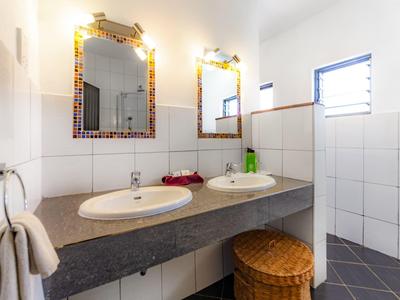 Licht badkamer met twee wastafels, decoratieve spiegels en wasmand onder het aanrecht.