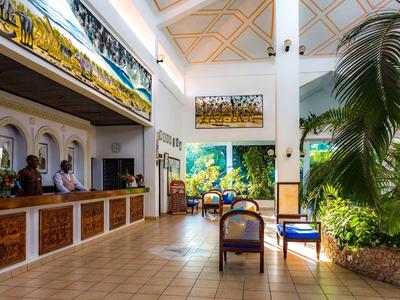 Lichte hotellobby met receptie, zithoek en weelderige binnentuin.