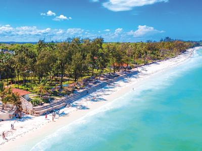 Lange zandstrand met palmbomen en turquoise water onder een blauwe lucht.