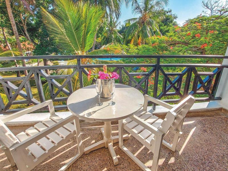 Balkon met witte tafel, stoelen en bloemen omgeven door weelderig tropisch groen.