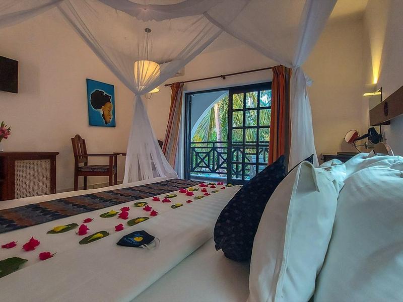 Knusse hotelkamer met muskietennet, balkon en versierde bedden.