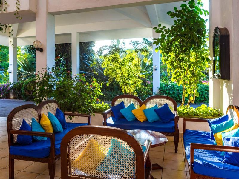 Gezellig zithoekje met blauwe kussens en kleurrijke kussentjes in een lichte serre.