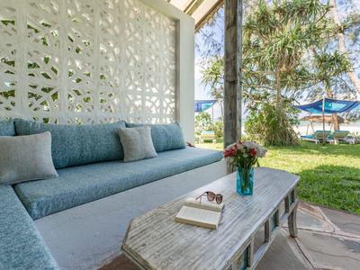 Cozy seating area with sofa and wooden table overlooking garden with sea view and sun umbrellas