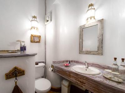 Small bathroom corner with wooden vanity, mirror, and toilet in a white room.