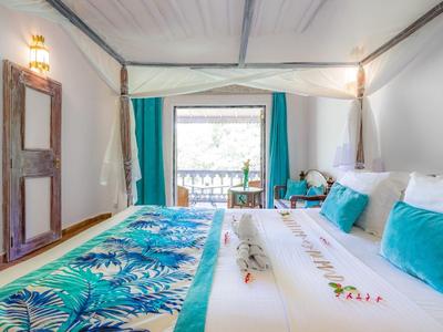 Gemütliches Hotelzimmer mit farbenfroher Bettwäsche und Blick auf einen Balkon mit Bergpanorama.