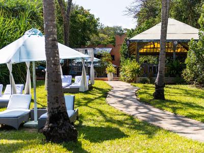 Green garden with cozy white loungers and pavilions on a sunny day.