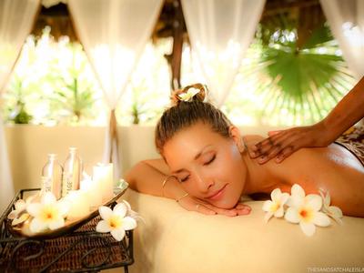 Woman relaxes during a massage in a bright spa room with flowers.