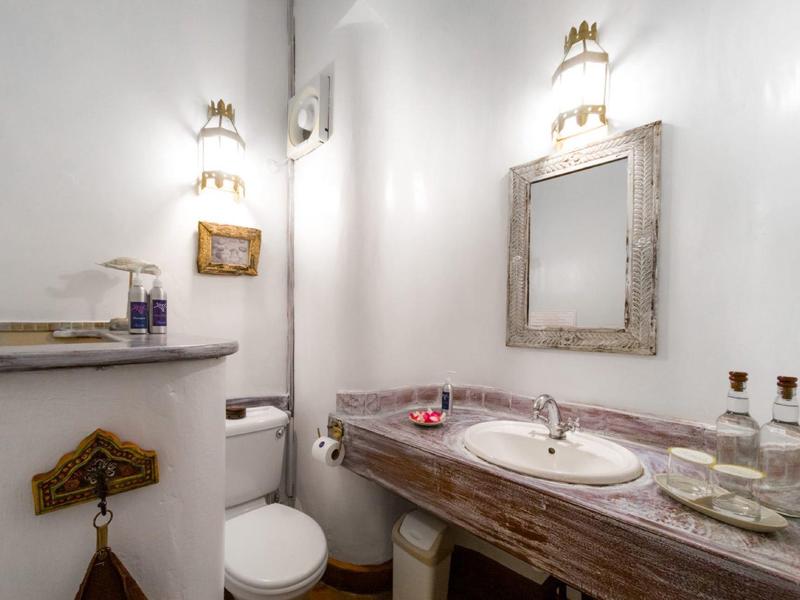 Small bathroom corner with wooden vanity, mirror, and toilet in a white room.