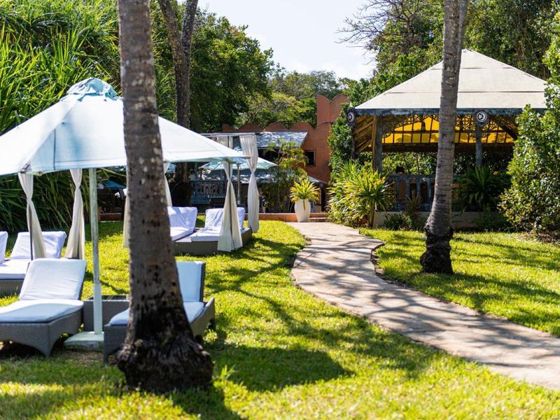 Green garden with cozy white loungers and pavilions on a sunny day.