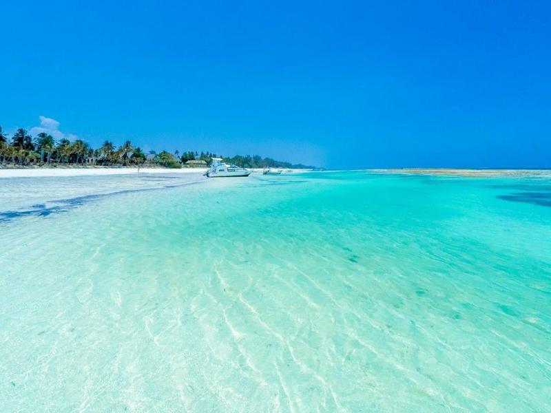 Clear turquoise water at white sandy beach under bright blue sky