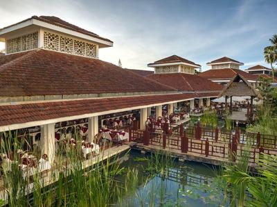 Hôtel traditionnel aux toits rouges, pont en bois et étang extérieur avec plantes