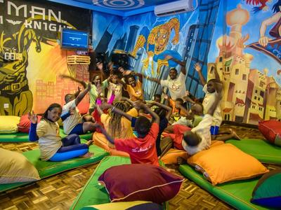 Espace enfant coloré et ludique avec coussins et fresques murales dans un hôtel.