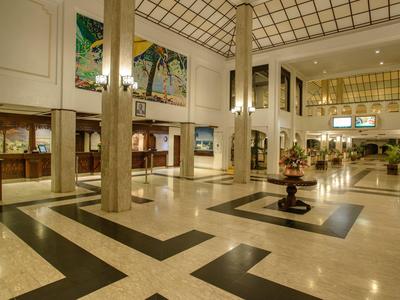 Grand hall d'hôtel avec sol en marbre, colonnes hautes et espaces lounge.
